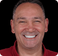 Smiling man with short dark hair and a red shirt, close-up portrait.