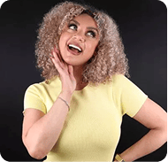 Happy woman with curly hair smiling and touching her face.