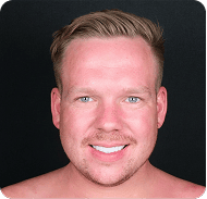 Smiling man with blonde hair and blue eyes in a close-up portrait.