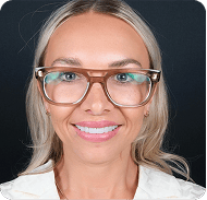 Smiling woman with glasses, blonde hair, and a white shirt, close-up portrait.