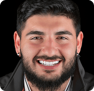 Smiling man with a beard and dark hair, wearing a black jacket and white shirt.