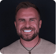 Smiling man with a beard and short hair in a professional portrait.