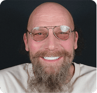 Close-up of a smiling man with glasses and a beard.