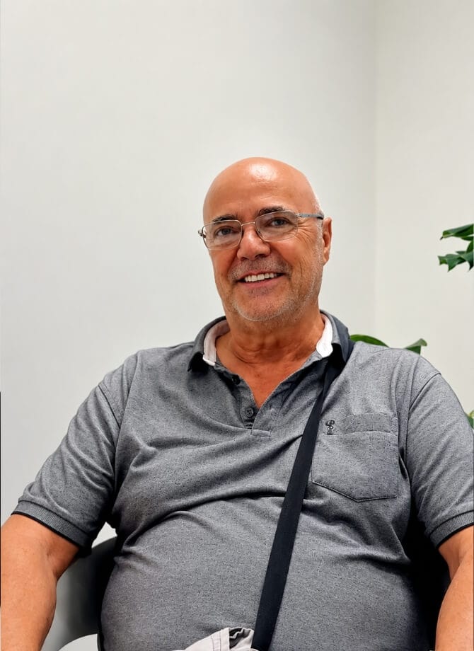 Smiling middle-aged man with glasses in a professional setting.
